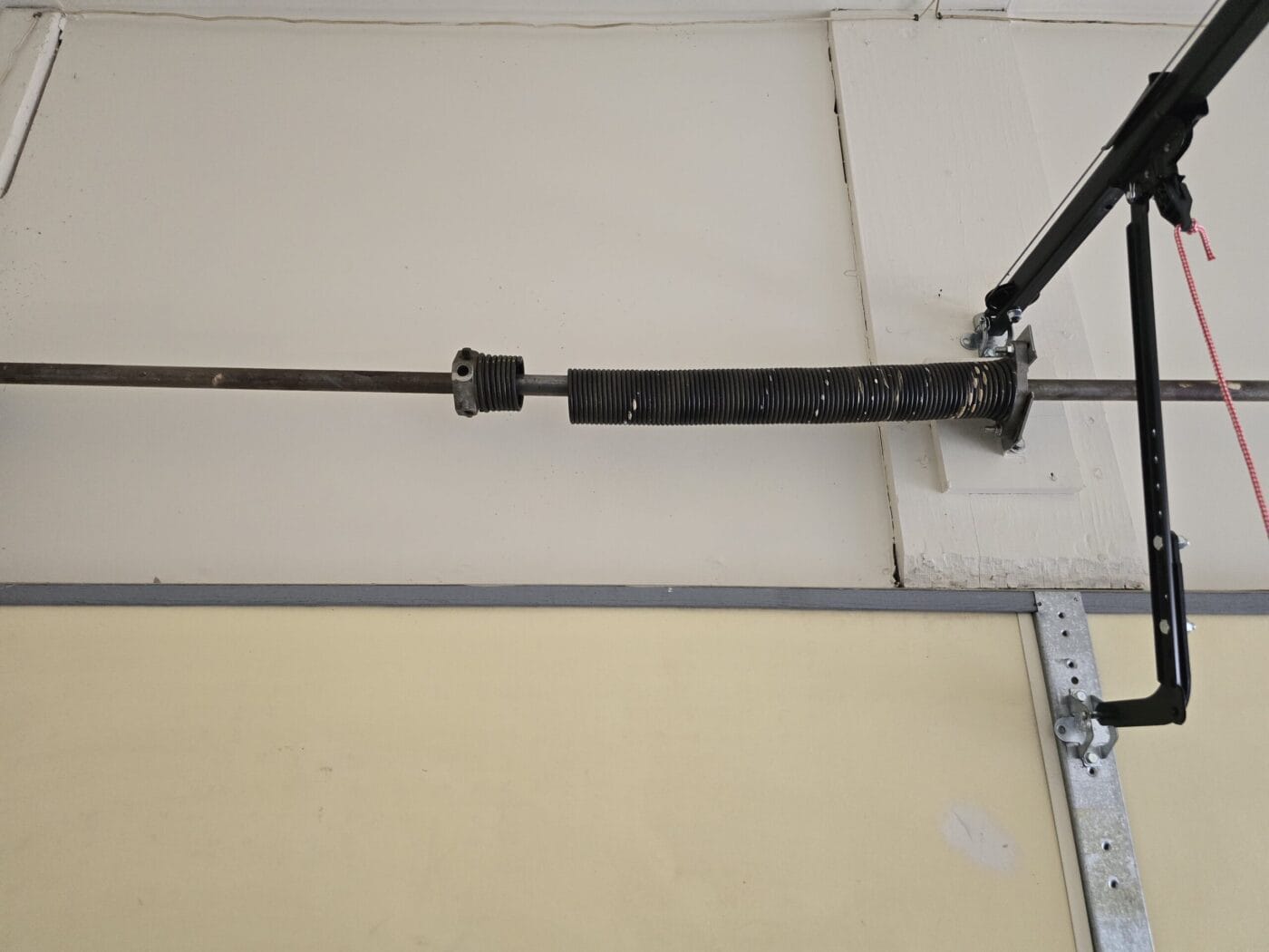 Garage door torsion spring installed on the ceiling with metal brackets and pulleys.